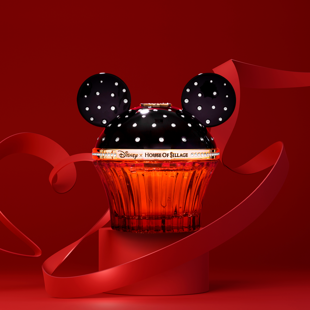 Disney x Honor of Billiage perfume bottle styled like a Mickey Mouse cupcake, featuring a black top with white polka dots and ears, and a red cupcake base, set against a red background with red ribbon.